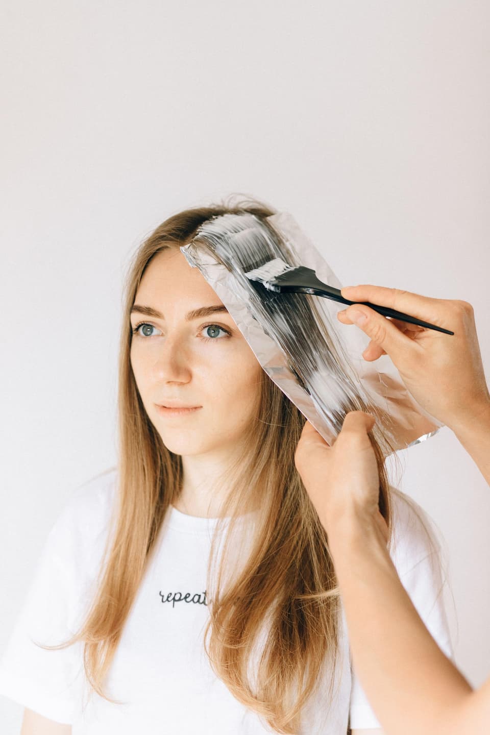A brush painting lightener through a section of blonde hair