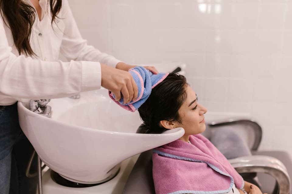 Client having her hair washed and towelled at the basin