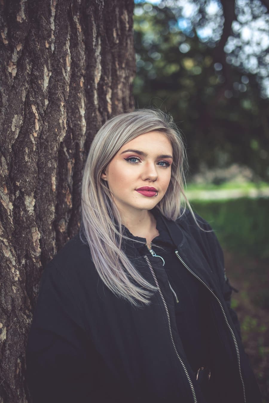Young woman with long silver ash hair beside a tree