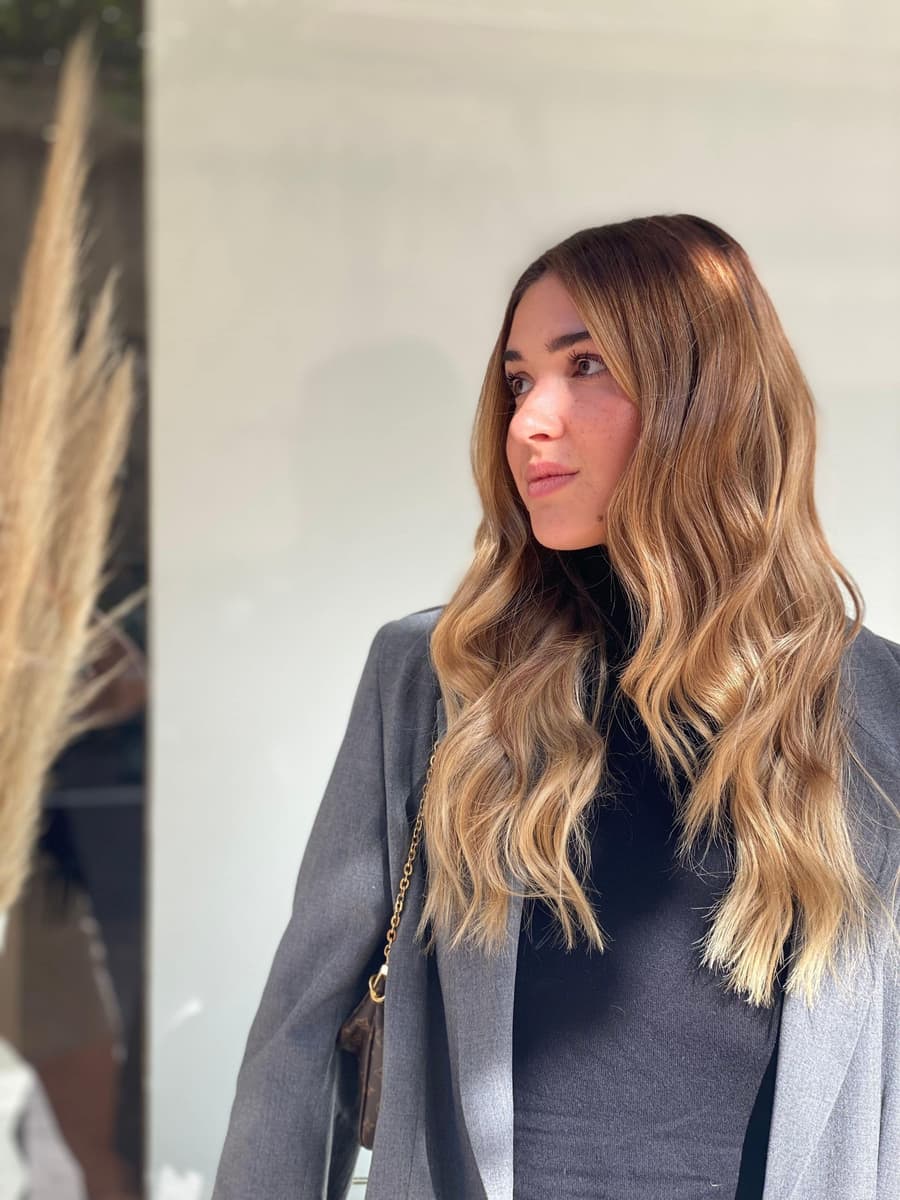 Woman with long honey balayage hair in a grey blazer